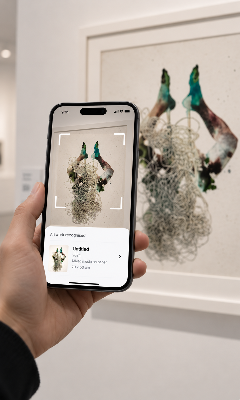 Visitor in a gallery pointing a phone at a framed mixed-media work; the scan overlay reads "Artwork recognised" and shows the piece with its year, medium and dimensions